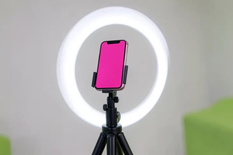 Um smartphone gravando um vídeo com um microfone externo e luzes de LED em um tripé.