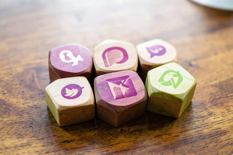 Uma pessoa organizando blocos com logos de redes sociais e ícones de marca em uma mesa.