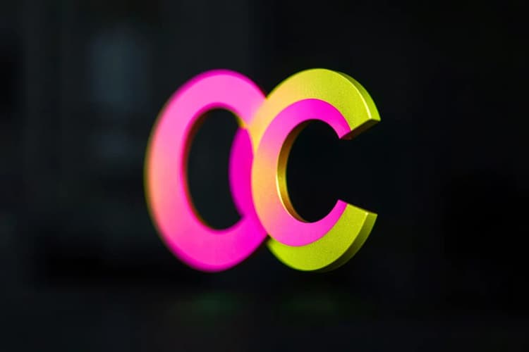 Um logotipo abstrato com as letras "CC" entrelaçadas em tons de dourado e rosa, sobre um fundo escuro e desfocado.