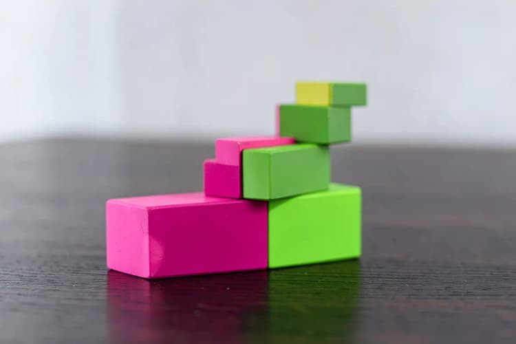 Uma pessoa organizando blocos de madeira coloridos em uma mesa.
