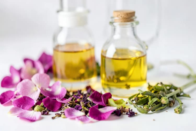 Um arranjo de ingredientes naturais como pétalas de flores e extratos de plantas ao lado de frascos de vidro com líquidos dourados, evocando a essência de produtos de beleza naturais.