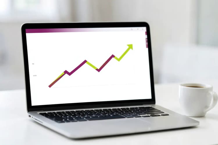 Um close-up de um laptop aberto exibindo um gráfico de crescimento estilizado em sua tela, com uma xícara de café ao lado.