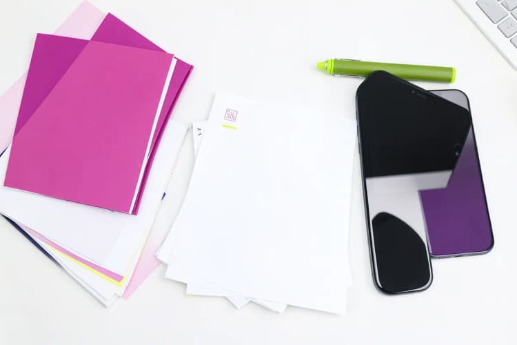 Uma composição de itens de escritório como papéis, canetas, um tablet e um celular organizados sobre uma mesa, representando a estrutura de um briefing.